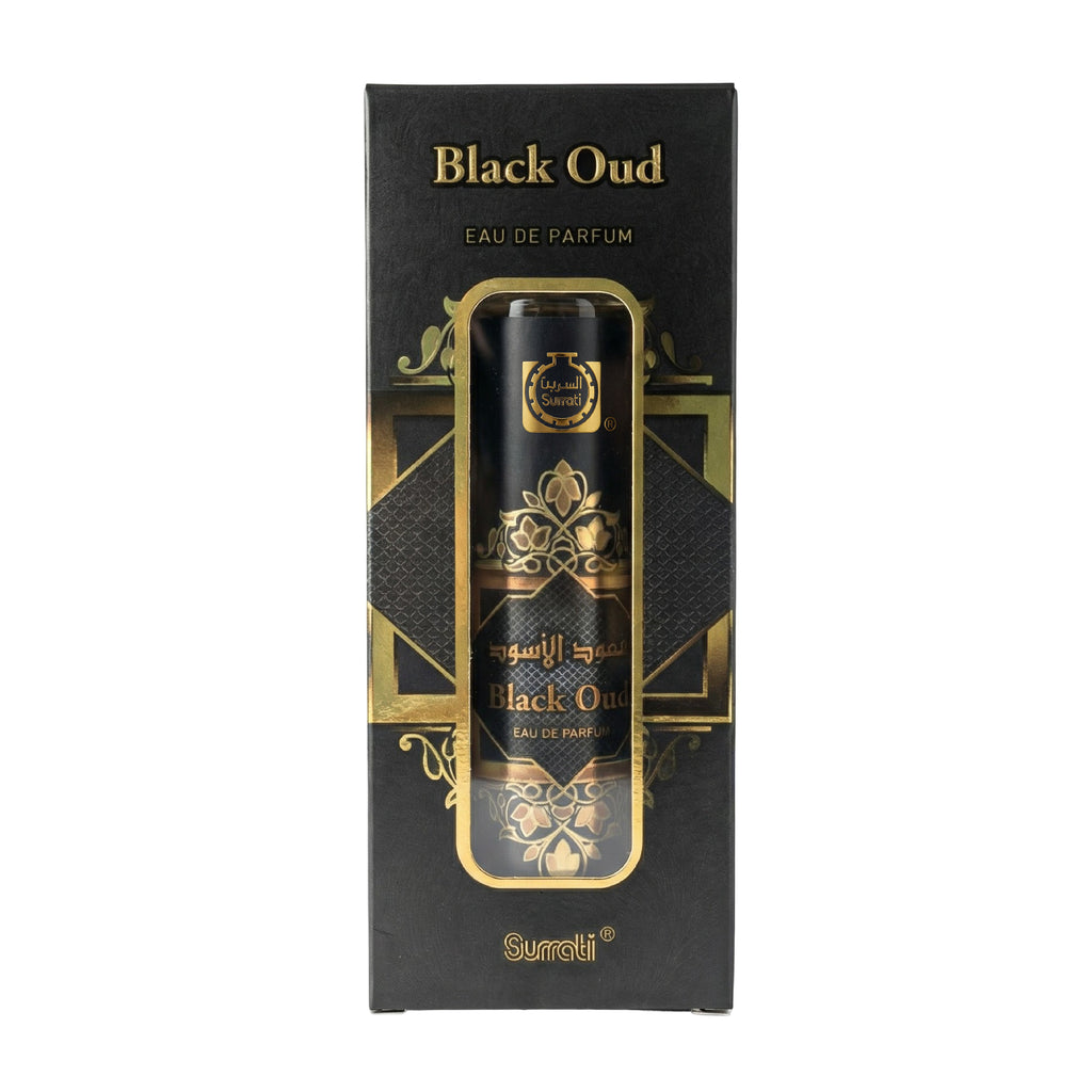 A bottle of Surati Black Oud Eau de Parfum next to its black and gold retail box, featuring elegant gold Arabic and English lettering on a white background.