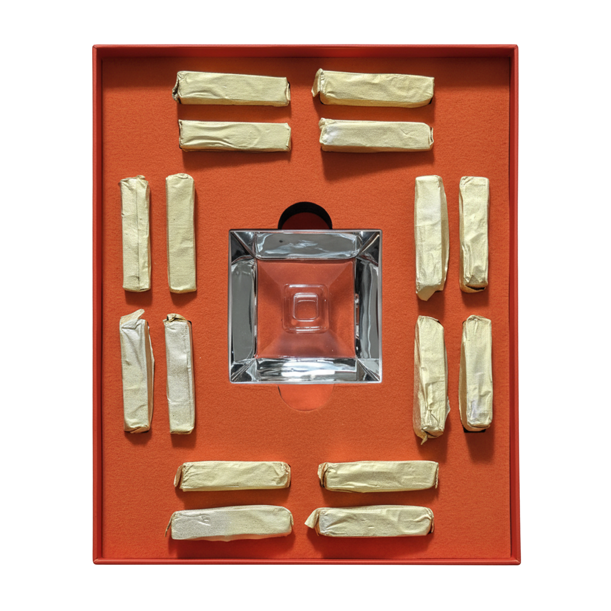 A square clear glass ashtray displayed in a red-orange presentation box, surrounded by multiple cream-colored rolled paper napkins on a white background.