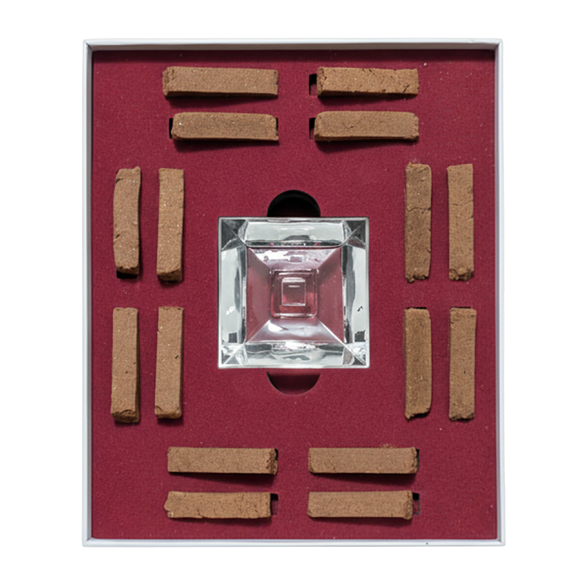 A square glass perfume atomizer bottle displayed in a red velvet-lined box with eight brown incense sticks arranged around it.