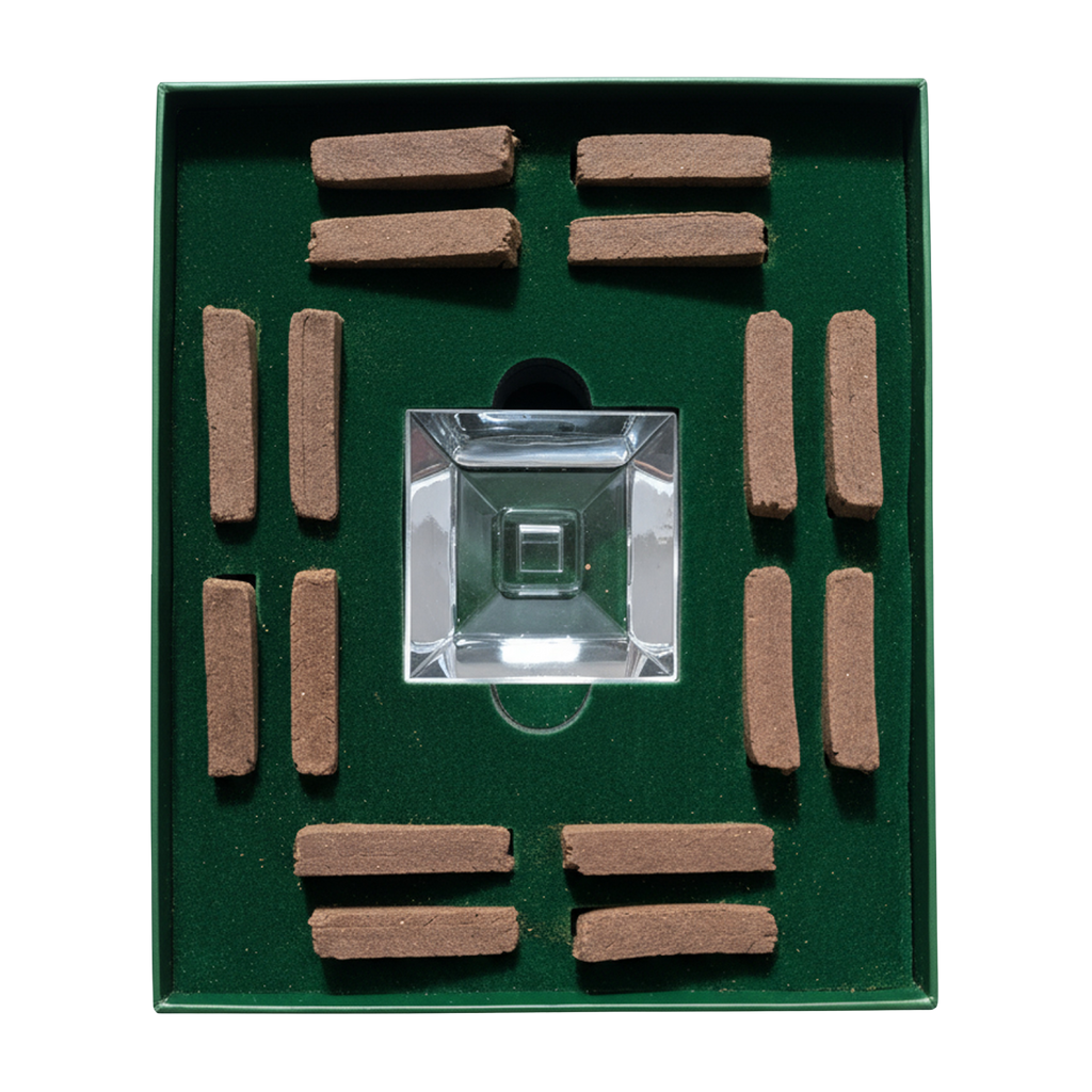 A square green presentation box containing a clear glass or acrylic square centerpiece surrounded by multiple small brown rectangular sticks, photographed on a plain white background.