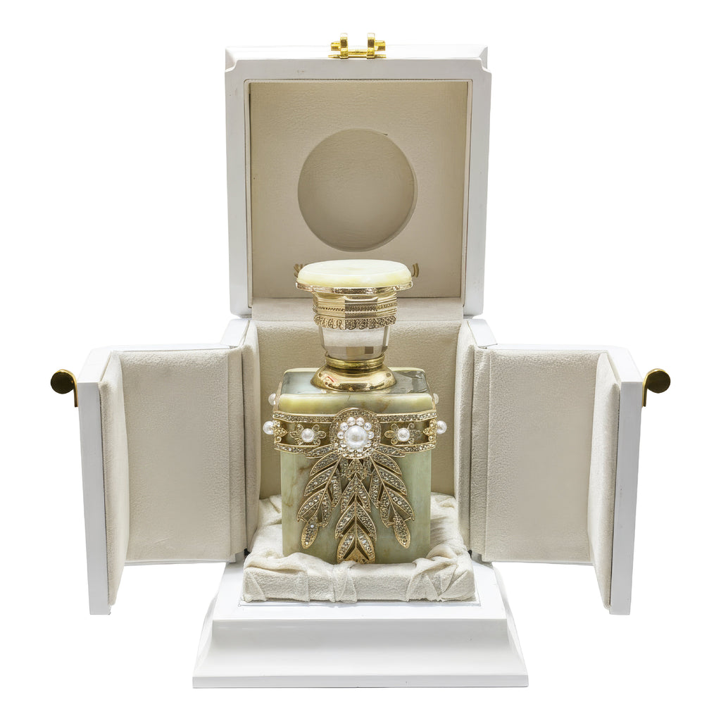 Decorative perfume bottle with gold accents in an open white box on a white background