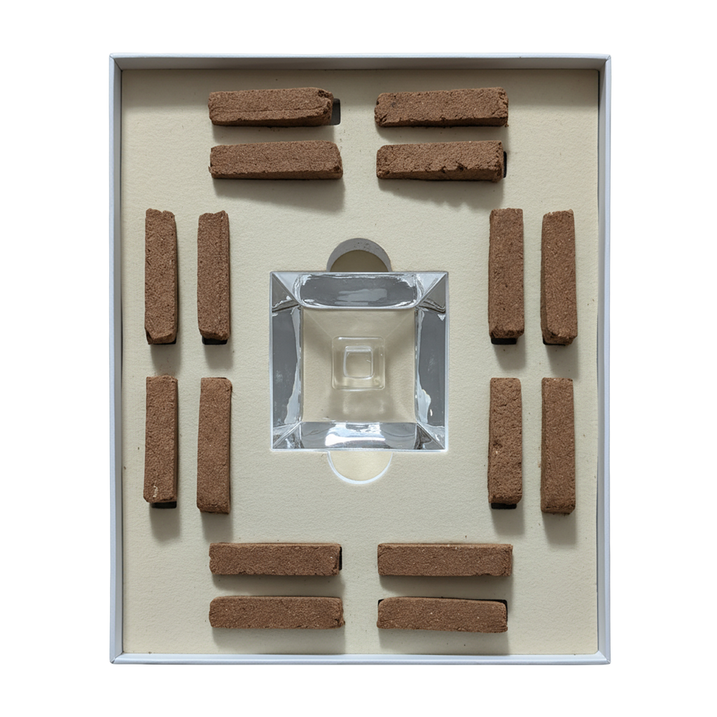 A boxed set of incense sticks arranged symmetrically around a clear glass incense holder on a cream-colored insert, photographed from above against a white background.