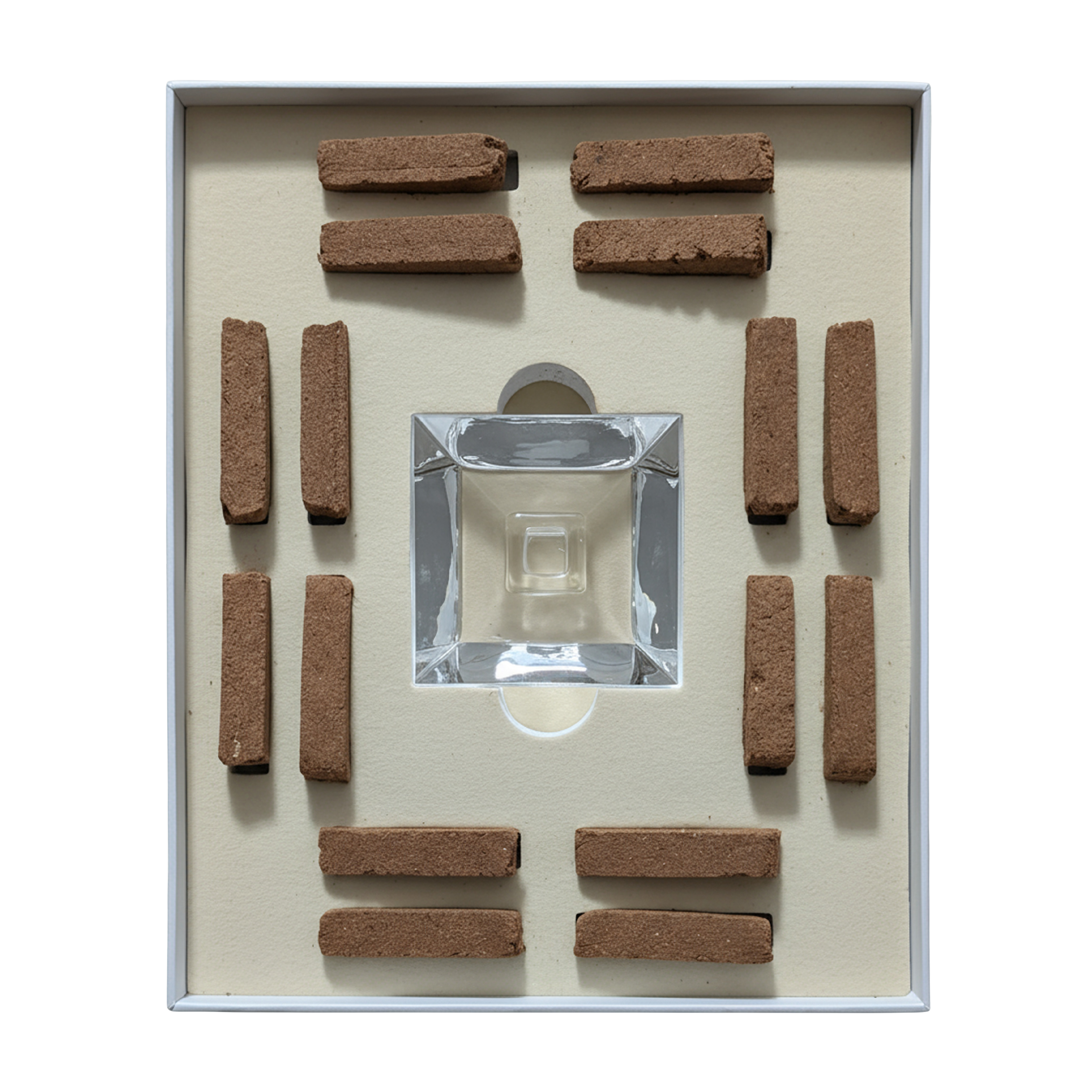A boxed set of incense sticks arranged symmetrically around a clear glass incense holder on a cream-colored insert, photographed from above against a white background.