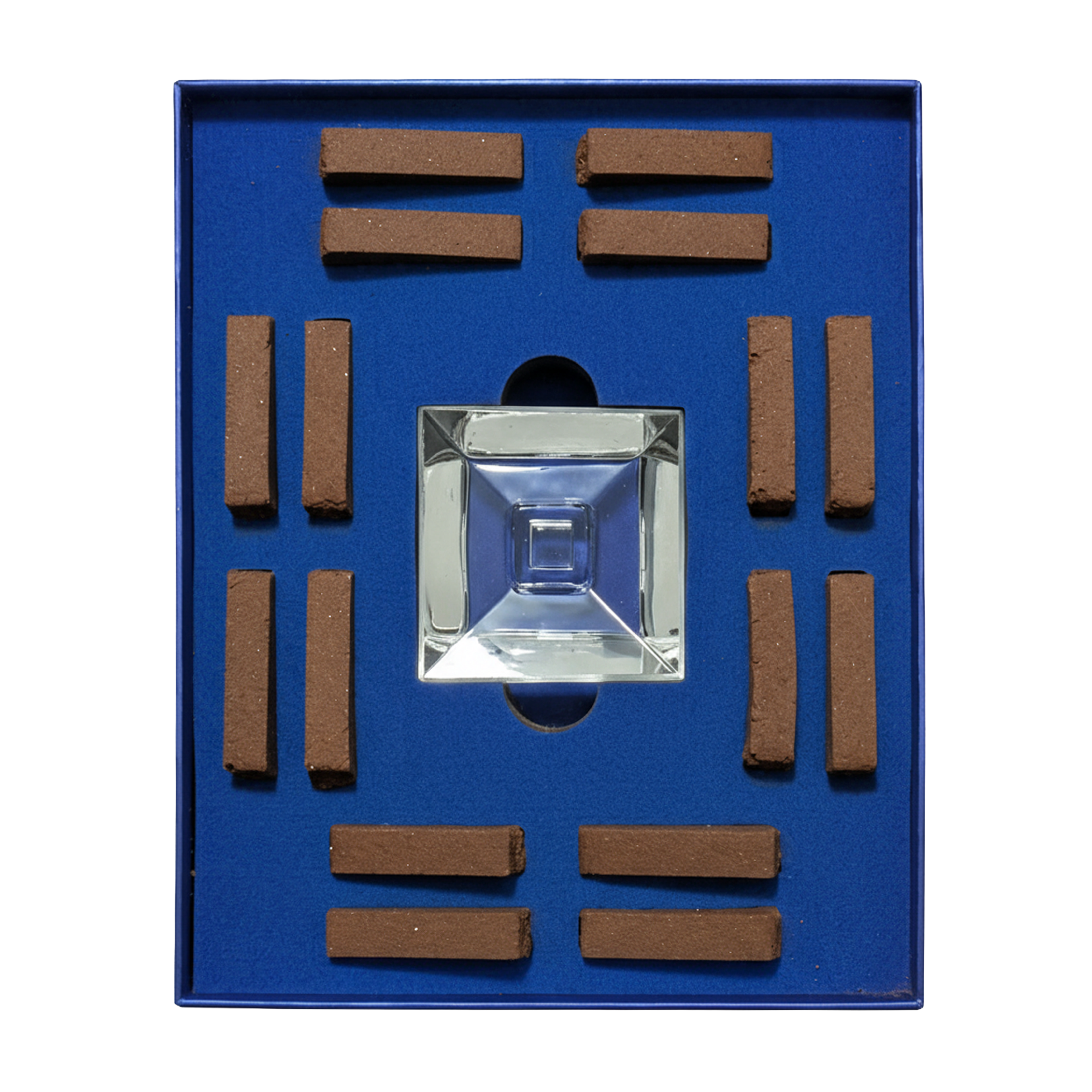 A square blue presentation box containing a clear faceted glass or acrylic pyramid in the center, surrounded by eight small brown rectangular sticks arranged in a grid.
