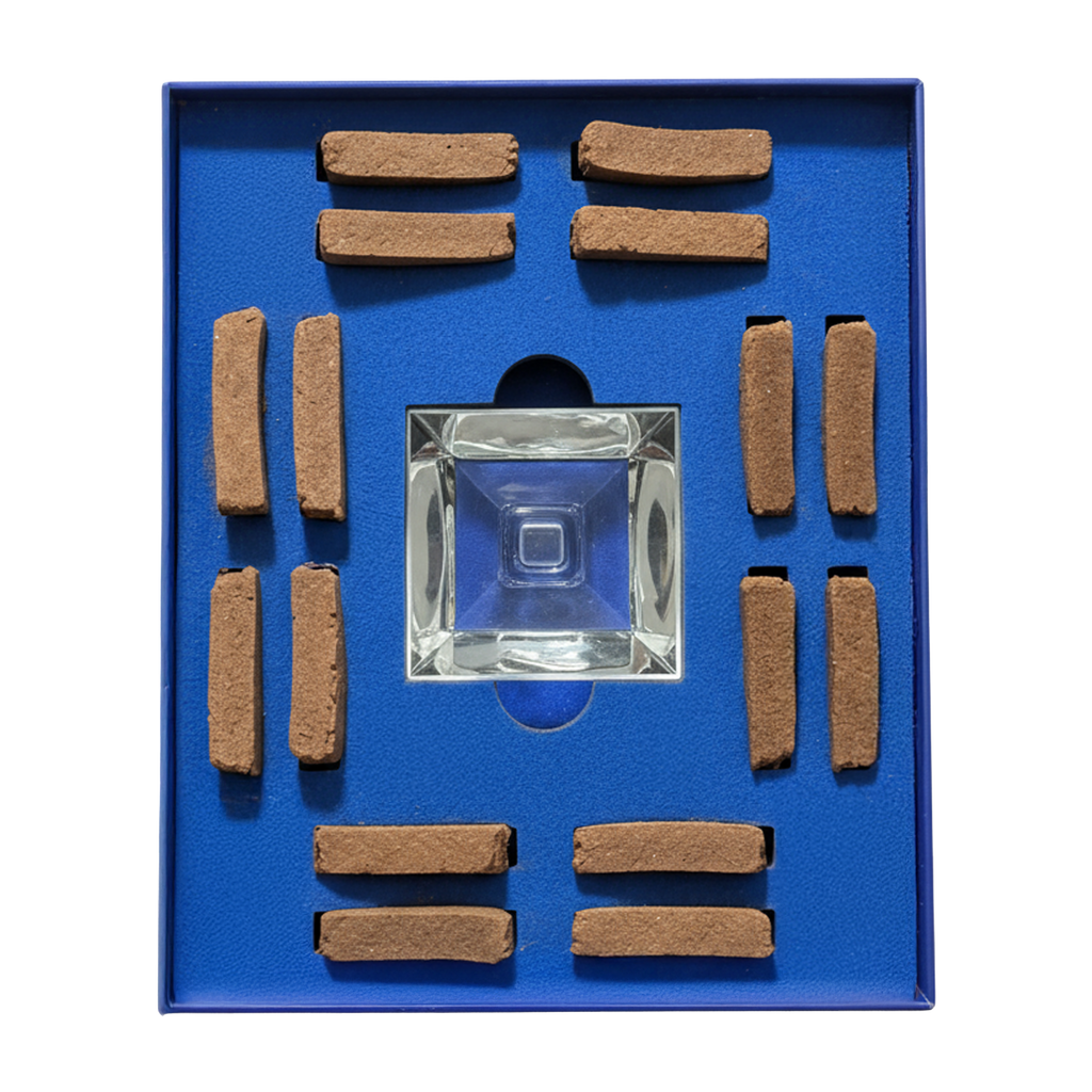 A square glass smoking pipe displayed in a blue presentation box with multiple brown rectangular tobacco pieces arranged around it.