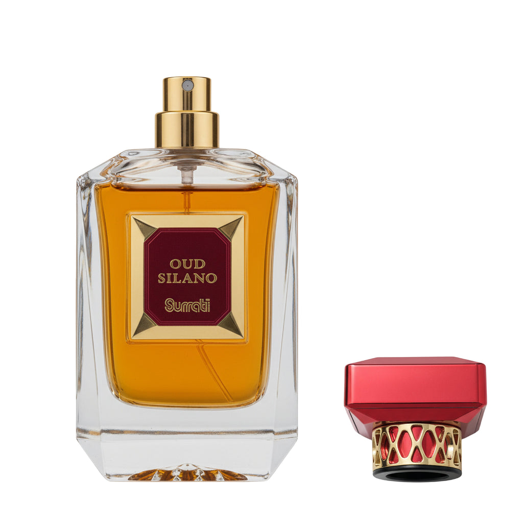 A clear glass perfume bottle filled with amber liquid, featuring a gold spray top and a maroon label with gold lettering that reads 'OUD SILANO' and 'Sourdi'. A matching red and gold cap is shown beside the bottle on a white background.